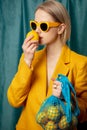 Stylish ukrainian woman in yellow sunglasses and jacket with lemons in net bag Royalty Free Stock Photo