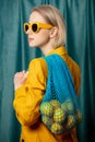 Stylish ukrainian woman in yellow sunglasses and jacket with lemons in net bag Royalty Free Stock Photo