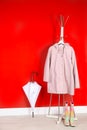 Stylish umbrella, raincoat and boots near red wall Royalty Free Stock Photo