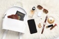 Stylish urban backpack and different items on white faux fur, flat lay
