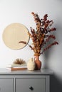 Stylish vases, dried eucalyptus branches and books on chest of drawers near white wall indoors. Interior design Royalty Free Stock Photo