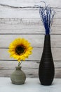 Stylish vases with fake sunflower and blue twigs