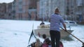 Stylish venetian boatman propelling gondola with foreign tourists, earning money