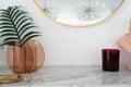 Stylish vertical view composition of red mirror table lamp with gold stationary on white marble top with copy space on white wall