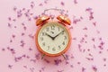 Stylish vintage alarm clock on pink background with lilac flower Royalty Free Stock Photo