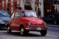 Vintage red FIAT 500 small Italian car in side view. grunge stucco elevation background