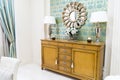 Stylish Vintage Style Home Interior with Wooden Commode and Decorated Mirror. Symmetrical Reading Lamps on Commode