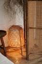 Stylish wabi sabi bedroom interior design with floor rattan lamp, bedside table and bamboo screen Royalty Free Stock Photo