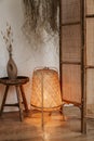 Stylish wabi sabi bedroom interior design with floor rattan lamp, bedside table and bamboo screen Royalty Free Stock Photo