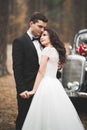 Stylish wedding couple, bride, groom kissing and hugging near retro car in autumn Royalty Free Stock Photo