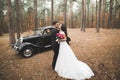 Stylish wedding couple, bride, groom kissing and hugging near retro car in autumn Royalty Free Stock Photo