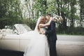 Stylish wedding couple, bride, groom kissing and hugging on retro car Royalty Free Stock Photo