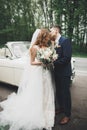 Stylish wedding couple, bride, groom kissing and hugging on retro car Royalty Free Stock Photo