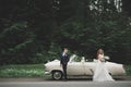 Stylish wedding couple, bride, groom kissing and hugging on retro car Royalty Free Stock Photo