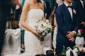 Stylish wedding couple standing in church for holy matrimony. Beautiful bride and groom praying at wooden altar in church, wedding