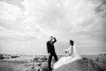 Stylish wedding couple standing on sea shore. Newlyweds are walking by the sea. Black and white