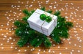 Stylish white Christmas gift box with green baubles on fir tree branches and wooden background Royalty Free Stock Photo