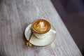 Hot white cup of cappuccino with latte art on wooden table
