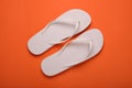 Stylish white flip flops on orange background, top view Royalty Free Stock Photo