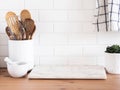 Stylish white kitchen background with kitchen utensils standing on wood countertop near white wall tiles Royalty Free Stock Photo