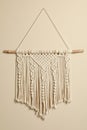 Stylish white macrame hanging on beige wall