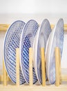 Stylish white plates with blue patterns stand in a wooden stand.