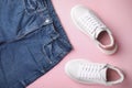 Stylish white sneakers and jeans on pink background, flat lay Royalty Free Stock Photo