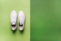 Stylish white sneakers and rope on green background with copy space. Top view. Minimal flat lay. Summer shoes collection Royalty Free Stock Photo