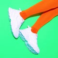 Stylish white Sneakers and vintage orange stockings on fresh green background. Sport fitness summer active vibes