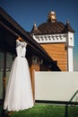 Stylish white wedding dress hangs by the hotel window against a blue sky Royalty Free Stock Photo