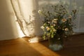 Stylish wildflowers bouquet in evening sunlight against window in rustic room. Beautiful summer flowers in vase gathered from Royalty Free Stock Photo