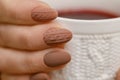 Stylish winter nail design. Knitted fabric texture on women& x27;s nails. A woman& x27;s hand holds a cup of warm drink. Royalty Free Stock Photo
