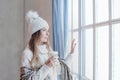 Stylish winter woman holding hot dring and resting at home, romantic portrait