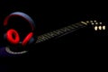 Stylish wireless headphone on a acoustic guitar on black background