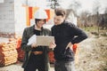 Stylish woman architect with tablet  and foreman checking blueprints at construction site. Young engineer and construction workers Royalty Free Stock Photo