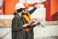 Stylish woman architect with tablet  and foreman checking blueprints at construction site. Young engineer and construction workers Royalty Free Stock Photo