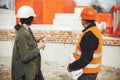 Stylish woman architect with tablet and senior foreman checking blueprints at construction site. Engineer and construction worker Royalty Free Stock Photo