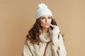 stylish woman in beige sweater, mittens and hat