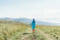 Stylish woman walking on rural field road in summer.