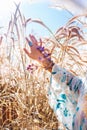 Stylish woman hand with ring anf flowers on the field in summer sun light