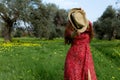 Stylish woman hides her face behind a straw hat. Nature love and freedom concept. Green field with yellow flowers . Glossy vogue