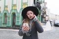 A stylish woman listens to music in the headphones on the background of a beautiful old town Royalty Free Stock Photo