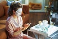 Stylish woman with facial mask using smartphone
