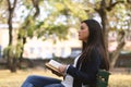 Stylish woman reading a book outdoors, while thinking Royalty Free Stock Photo