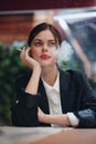 Stylish woman sits in a cafe at a table and smokes a cigarette releasing smoke from her mouth, a bad habit, a smile with Royalty Free Stock Photo