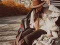 Stylish woman sitting with dog in car trunk on background of autumn trees. Road trip with pet Royalty Free Stock Photo