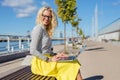 Stylish woman sitting ouside and working on laptop