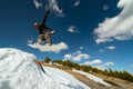 Stylish woman snowboarder makes a trick in flight. Snowboard jump from a kicker against the backdrop of mountains