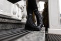 Stylish woman stands in a street in a shoes. Closeup of female legs in fashionable jeans in trendy leather black lace-up boots. Royalty Free Stock Photo