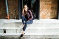 Casual style. Stylish woman in sunglasses sitting on the stone stairs. She dressed in jacket, skinny jeans and shoes. Long hair, e Royalty Free Stock Photo